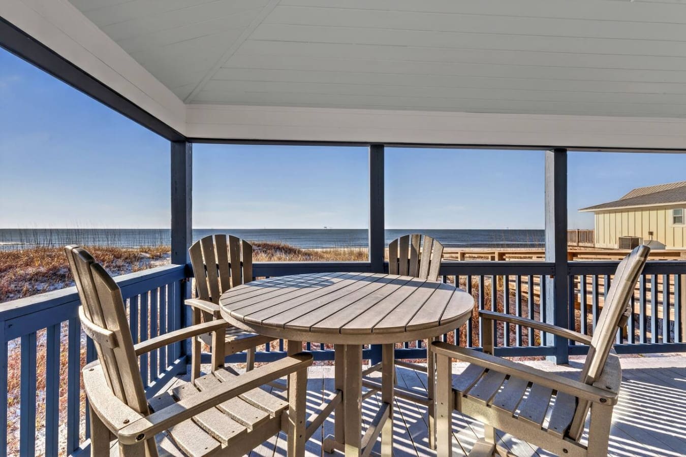 Oceanfront covered deck with Adirondack chairs and endless beach views—basically paradise if you never want to leave.
