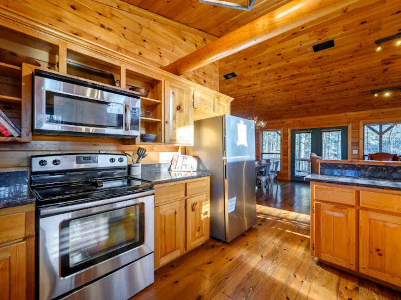 This gorgeous log cabin kitchen features stainless steel appliances, wood cabinetry, and amazing views of the forest.