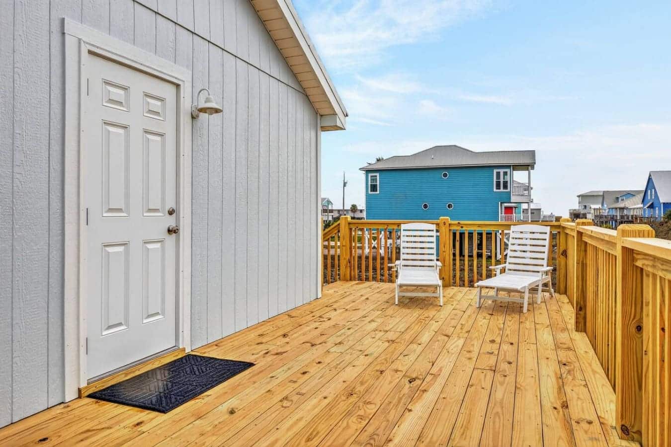 Spacious deck with ocean views, perfect for relaxing in the sun with neighbors' colorful beach houses dotting the horizon.