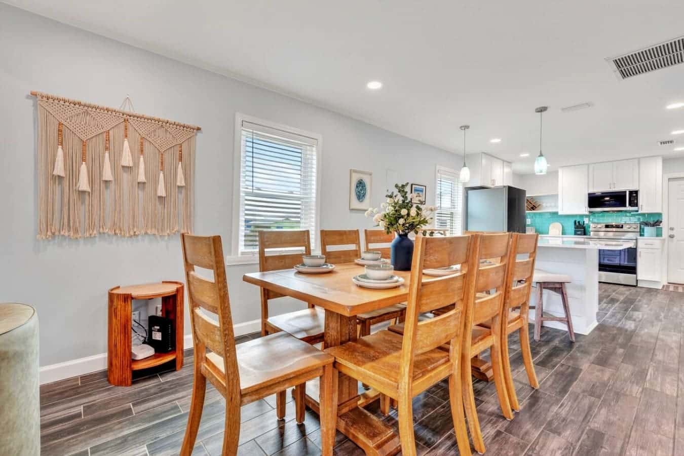 Open concept dining and kitchen area with beautiful wood furnishings and plenty of natural light from oversized windows.