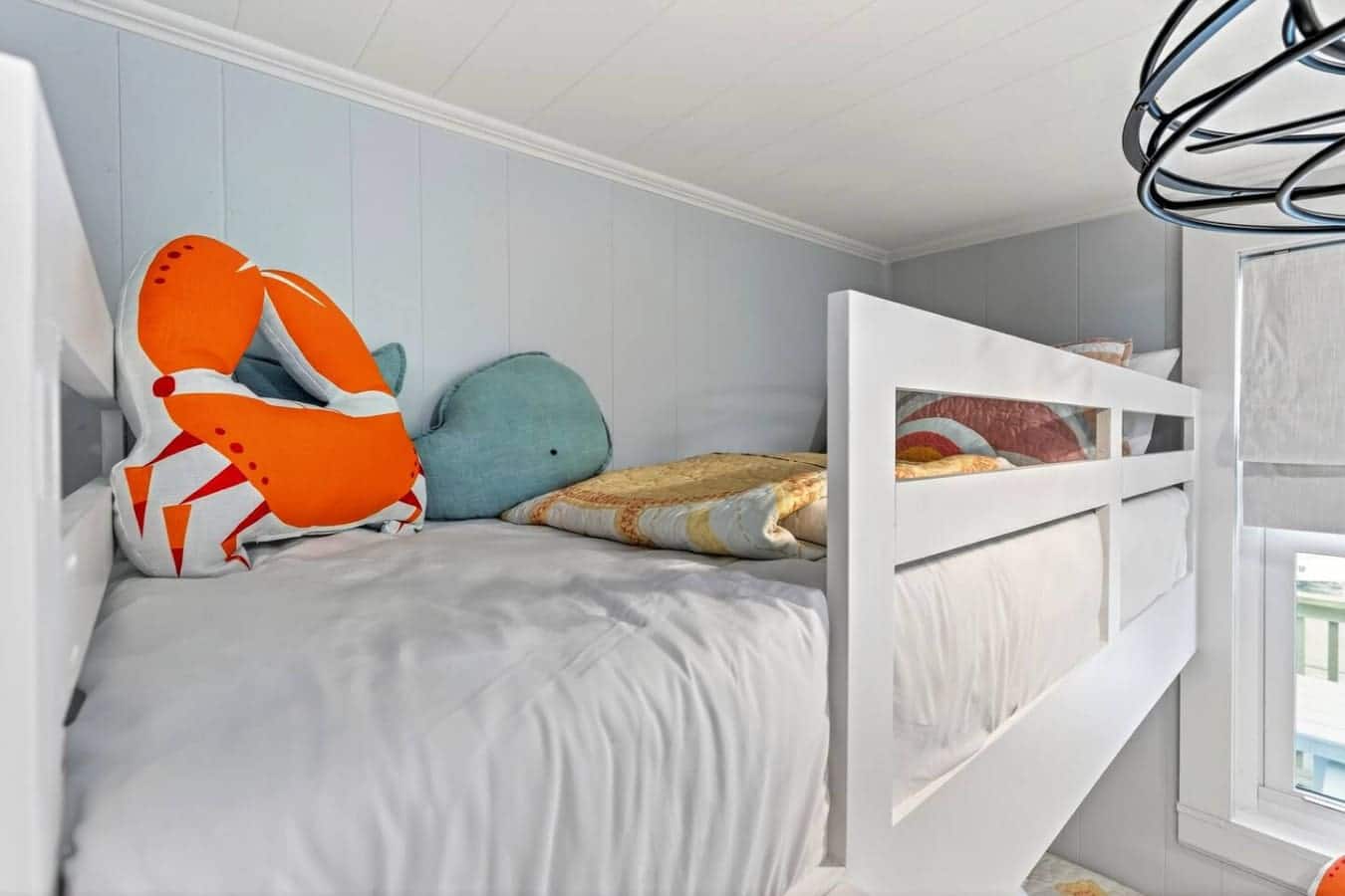 Cozy bunk room with ocean-themed decor and plenty of natural light from the window.