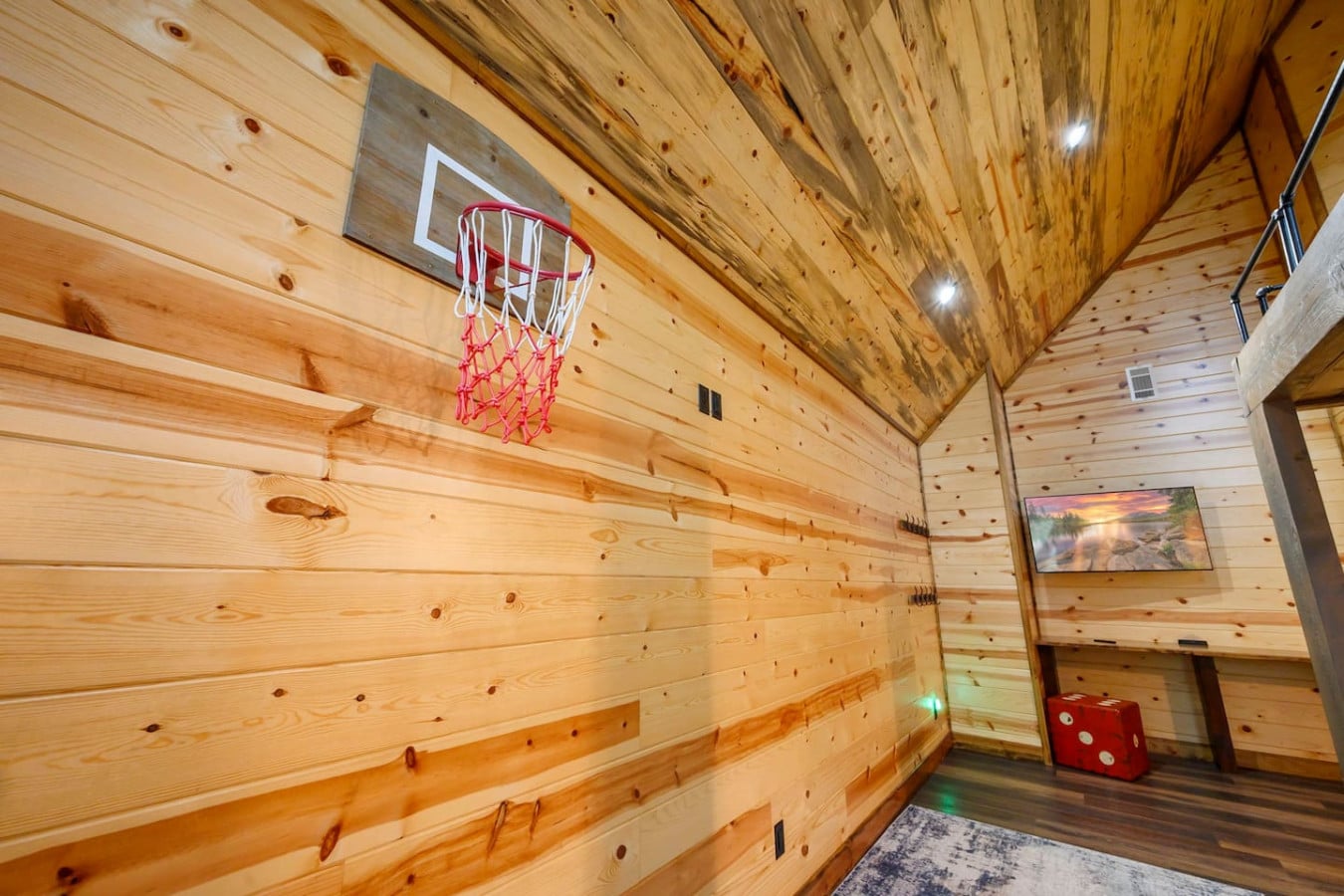 This cozy game room features wood walls, a basketball hoop, and plenty of space for indoor fun.
