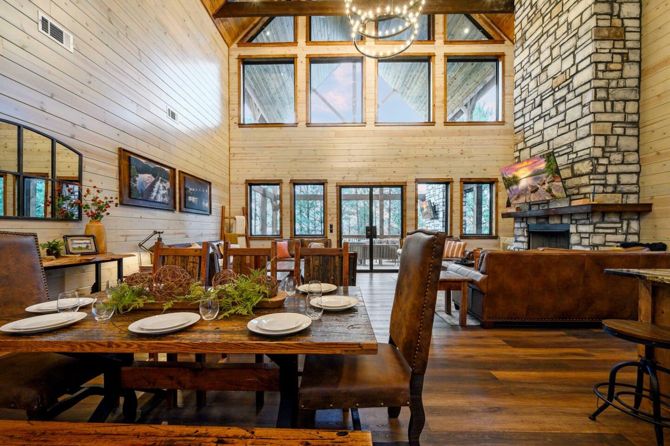 This stunning open-concept cabin features soaring ceilings, walls of windows, and a massive stone fireplace perfect for gathering.