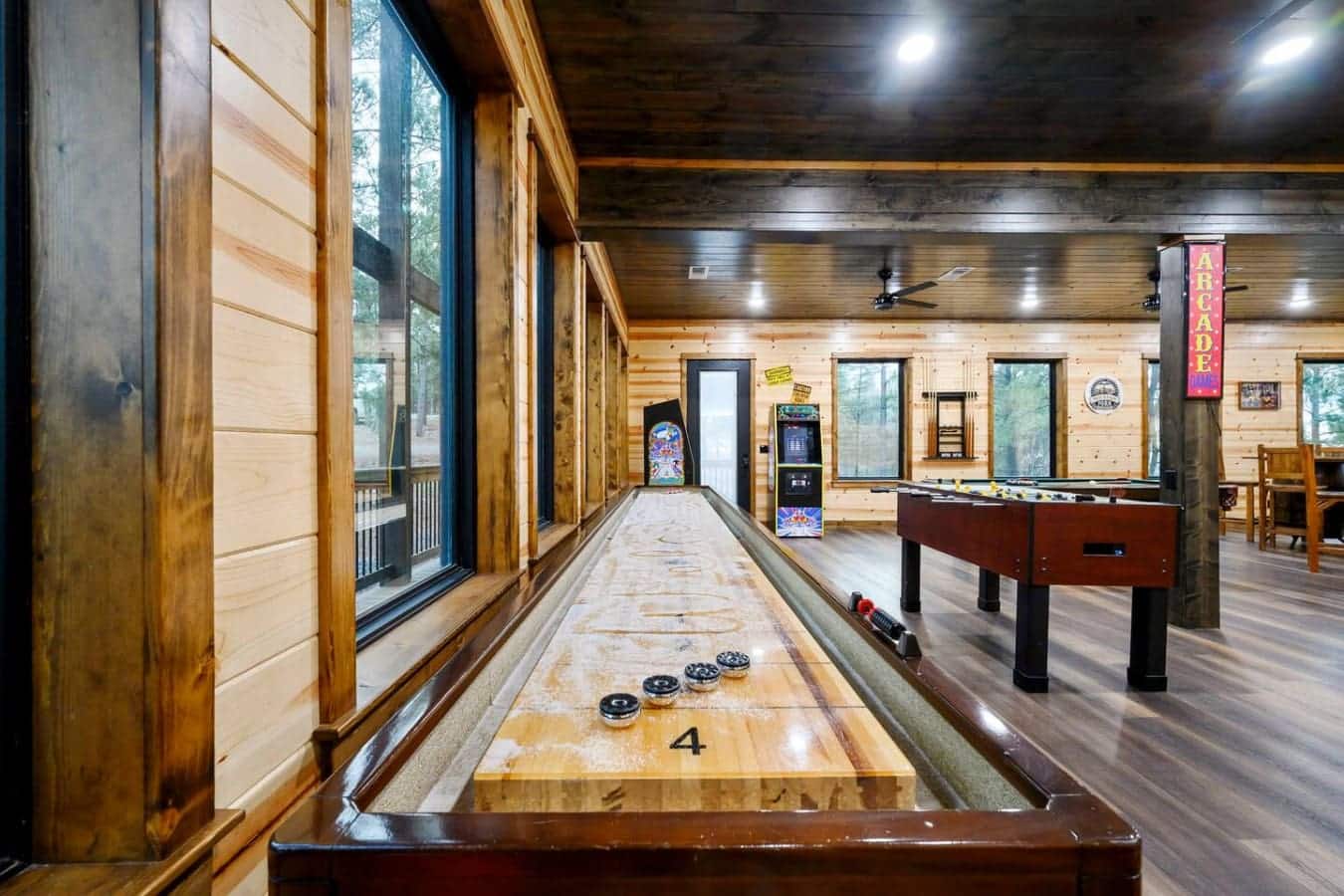 This game room has a shuffleboard table, foosball, arcade games, and tons of natural light from those huge windows.