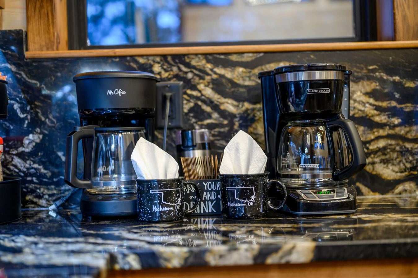 Beautiful granite countertops with a view of the lake through the window behind this well-equipped kitchen setup.