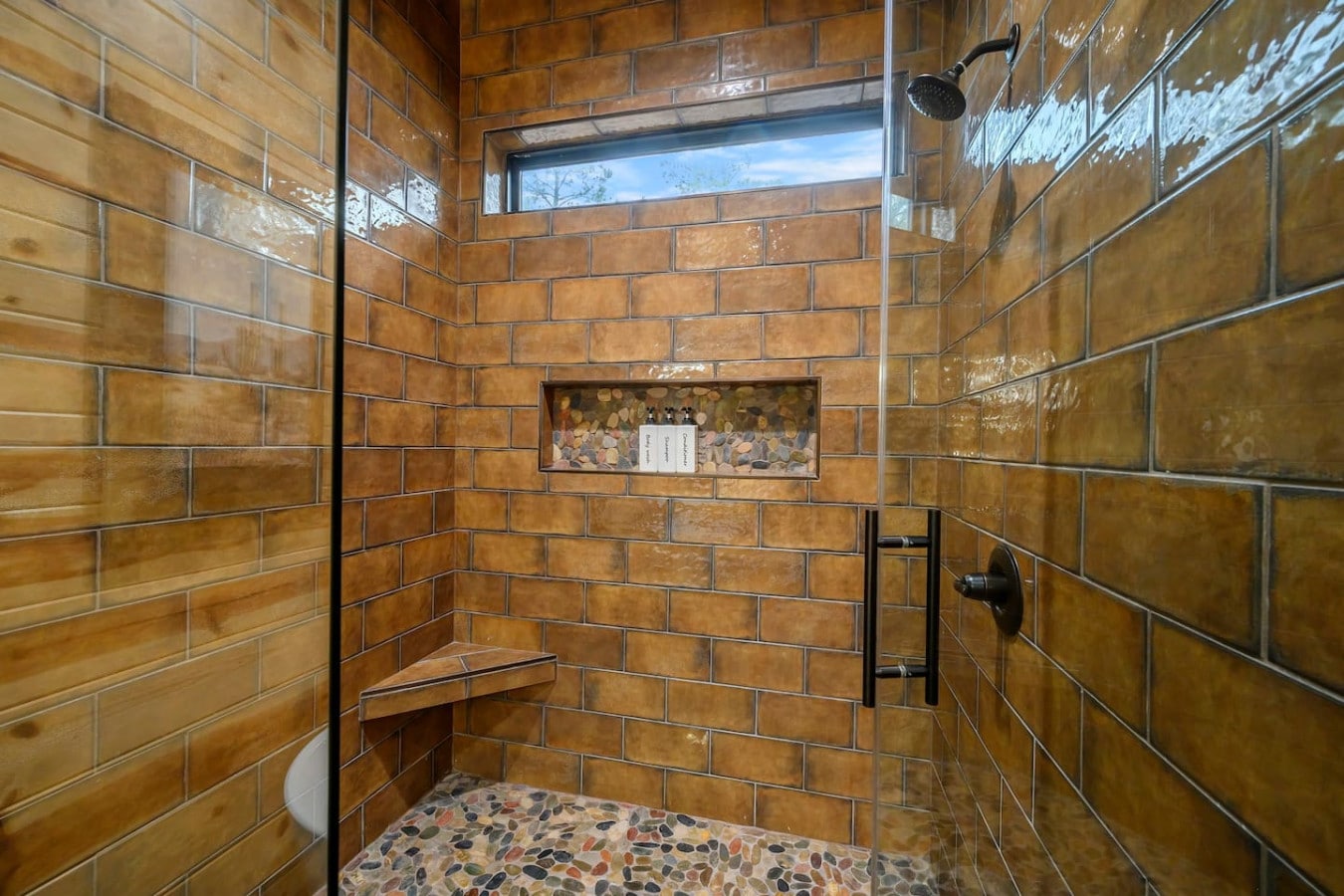 Gorgeous walk-in shower with warm tile work and a skylight that floods the space with natural light.
