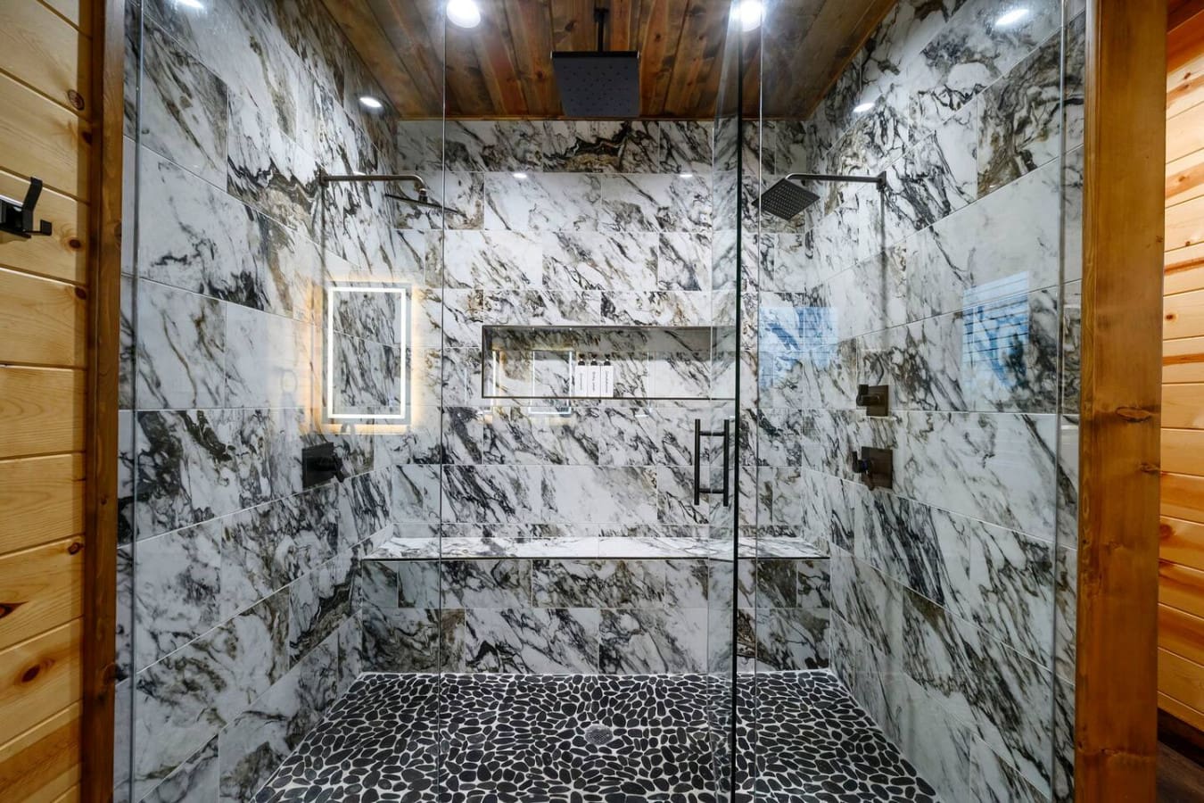 This marble shower is absolutely stunning with those veined tiles and a rainfall showerhead that makes you feel like you're at a high-end spa.