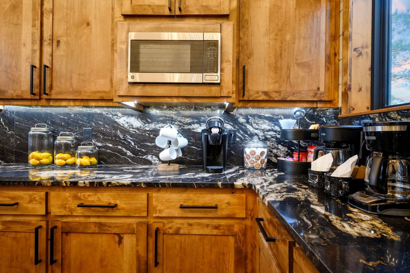 This kitchen features stunning black marble countertops and warm wood cabinetry with stainless steel appliances.