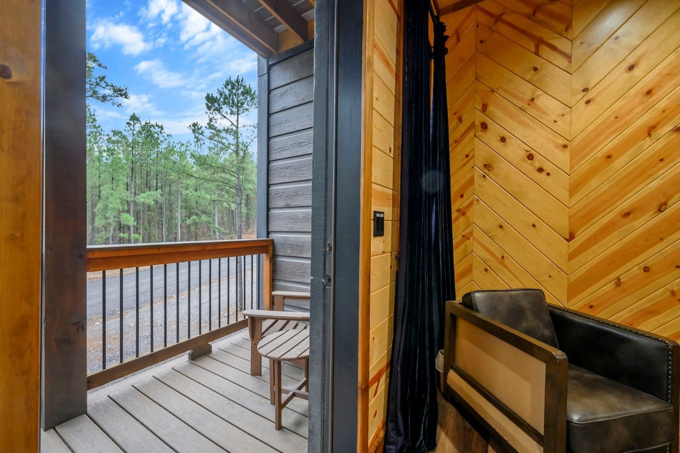 This cabin bedroom opens to a private deck with forest views and a cozy spot to take in the morning air.