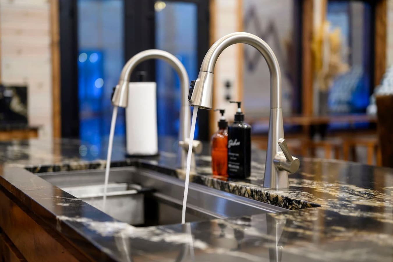 Modern kitchen with sleek stainless steel faucets and gorgeous granite countertops that overlook the living spaces.