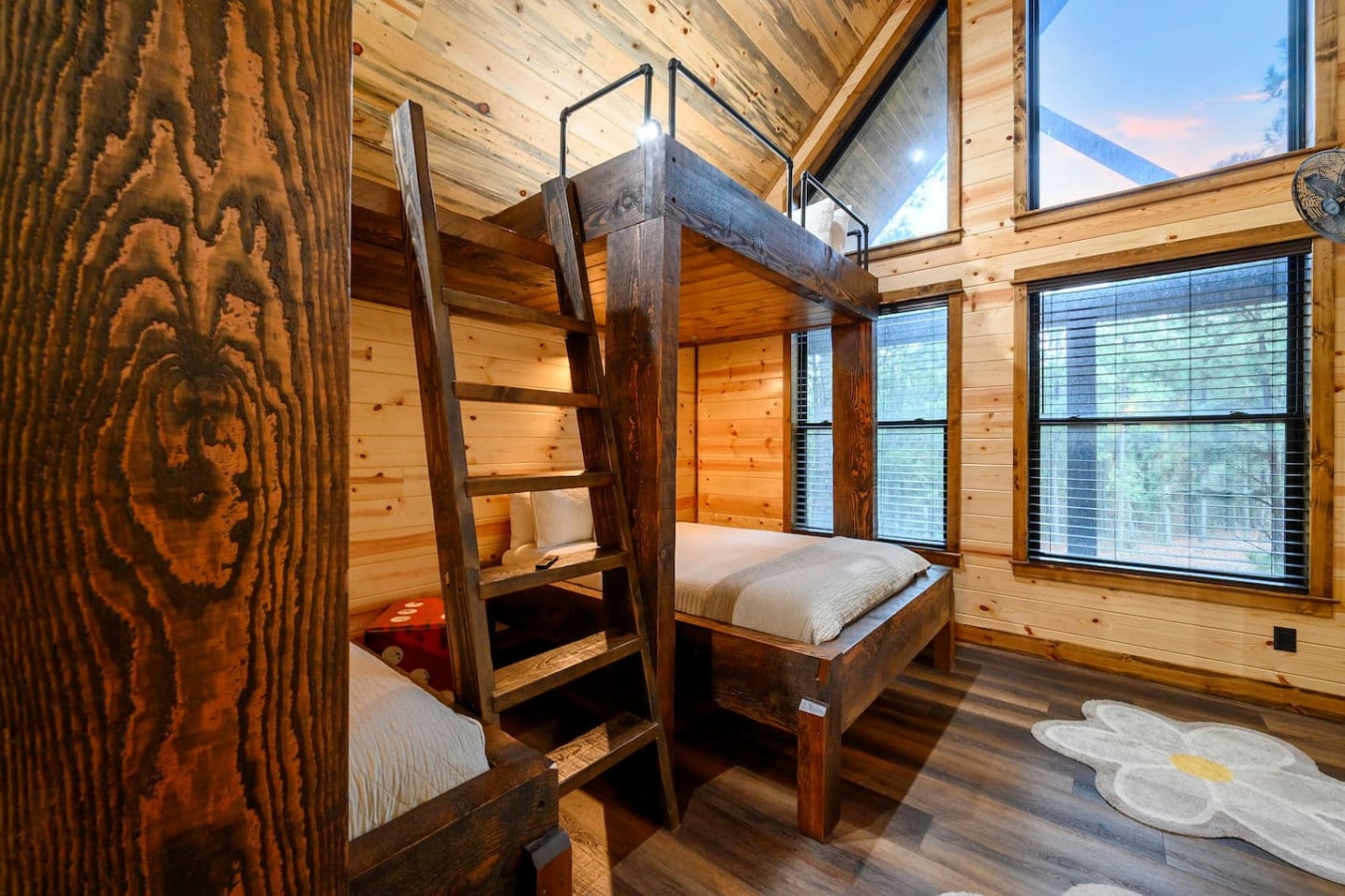 This cozy cabin bedroom features rustic bunk beds with mountain views through floor-to-ceiling windows.