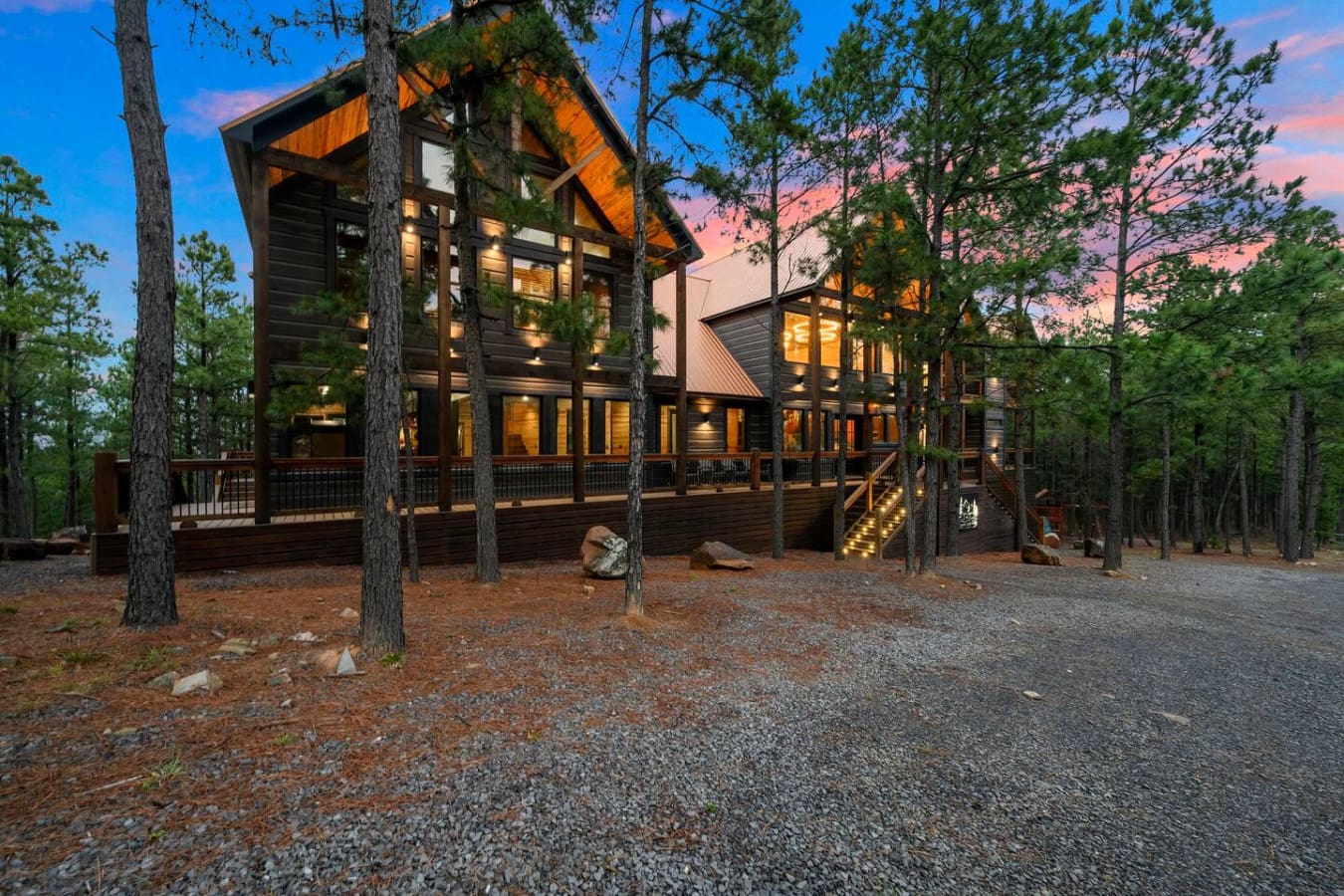 This stunning modern cabin sits elevated among towering pines with floor-to-ceiling windows and a wraparound deck perfect for sunset views.