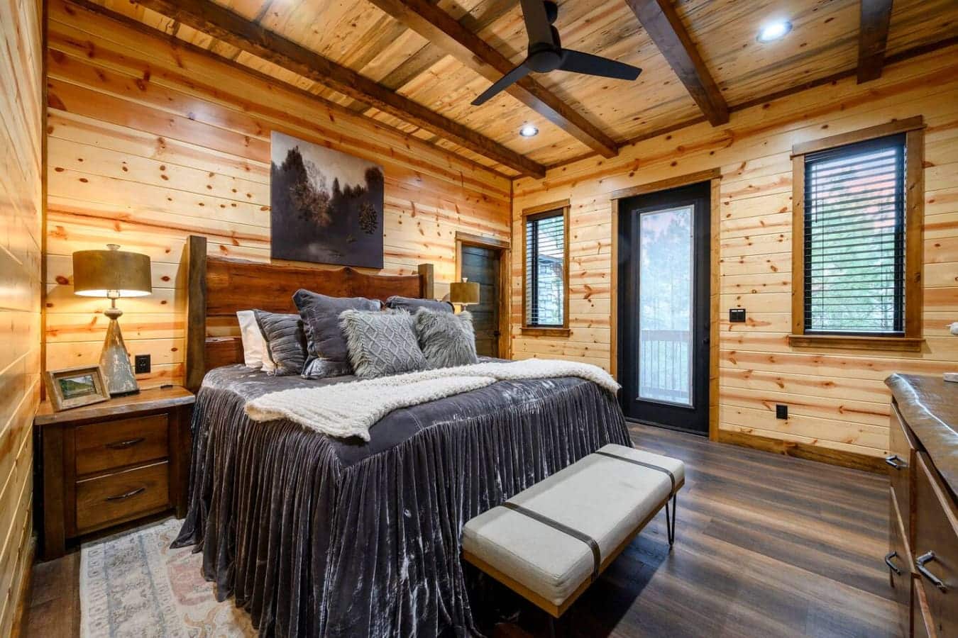 This stunning log bedroom features soaring ceilings, a cozy wood-burning aesthetic, and direct access to your private deck.