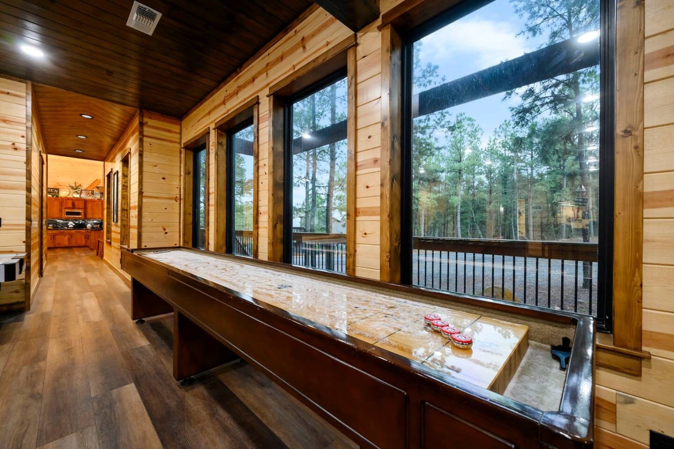 This wood cabin has massive windows overlooking the forest and a shuffleboard table for entertaining guests.