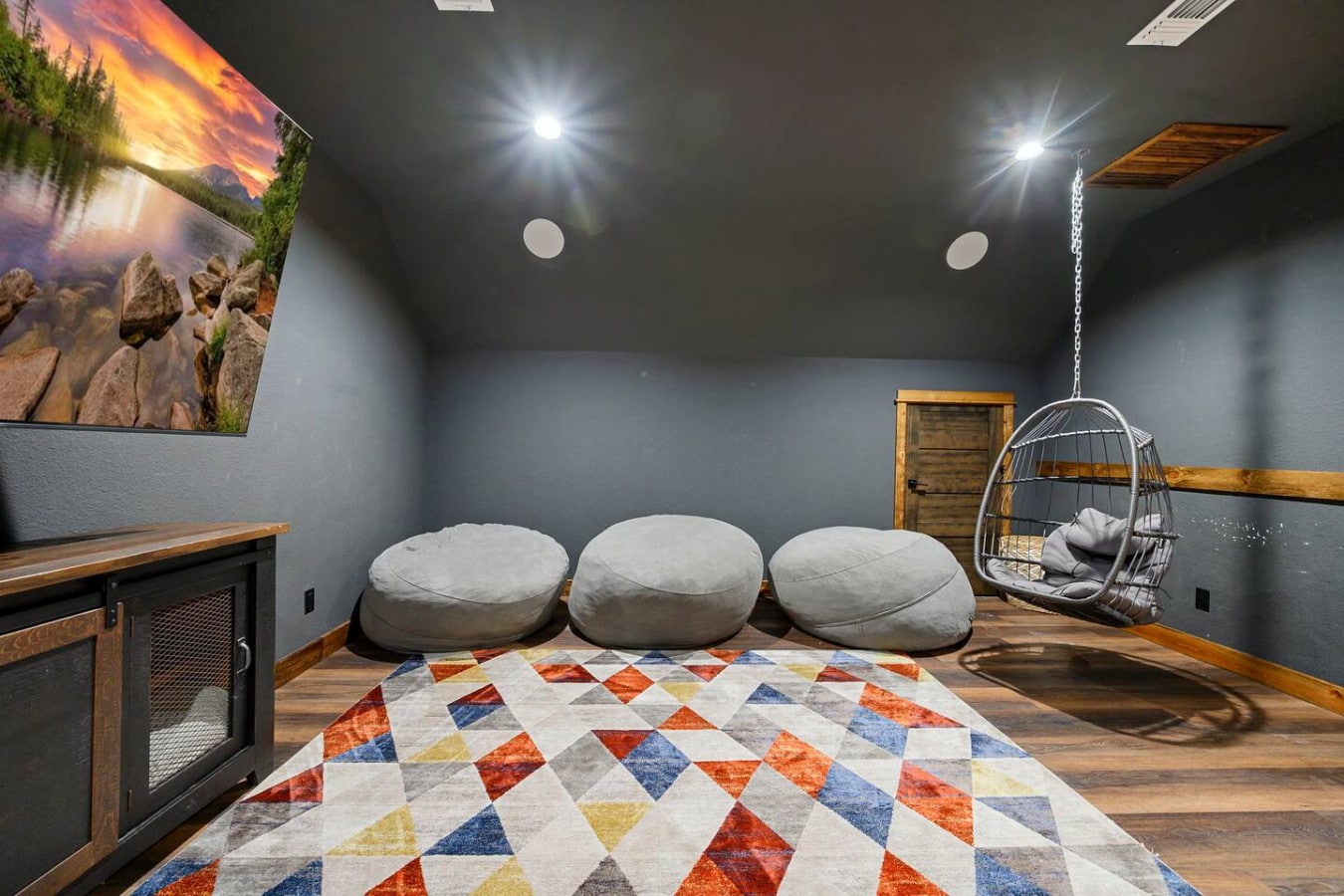 This cozy media room is perfect for entertaining with plush seating, a hanging chair, and ambient lighting throughout.