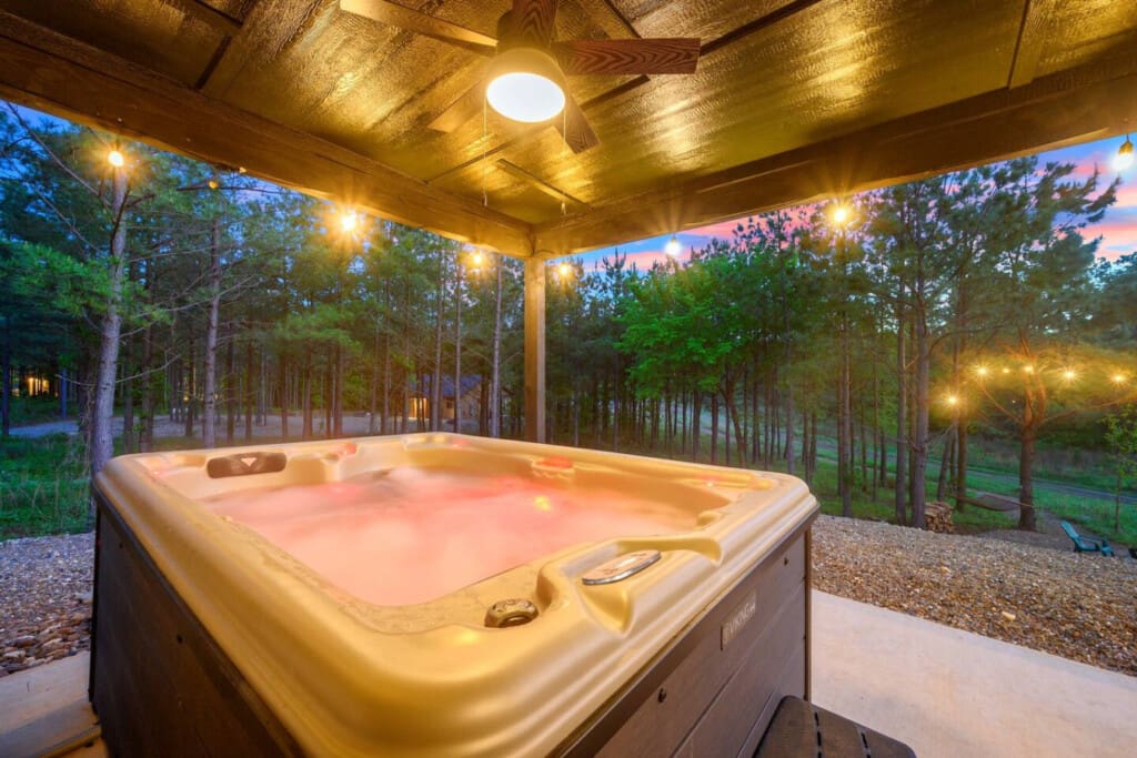 There's something seriously special about soaking in a hot tub under a covered patio as the forest fades into twilight and those warm lights make everything feel like your own private escape.