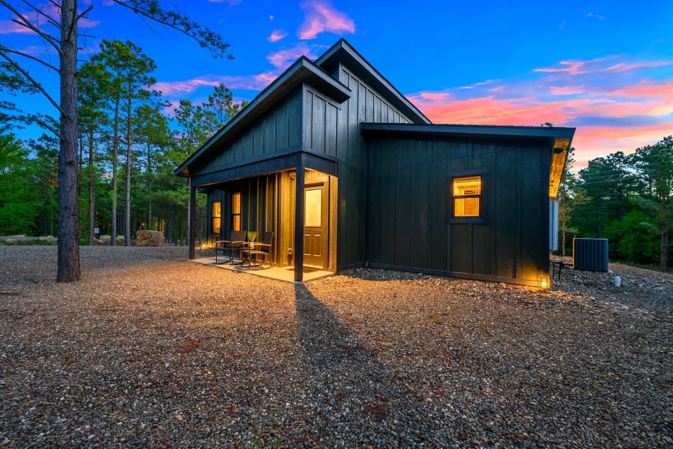 This sleek modern cabin glowing warmly against the twilight sky feels like your own private forest sanctuary, nestled perfectly among the towering pines with nothing but peaceful woodland vibes surrounding you.