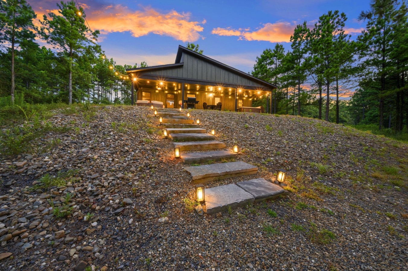 Lit stone steps create an inviting path up to the cabin.