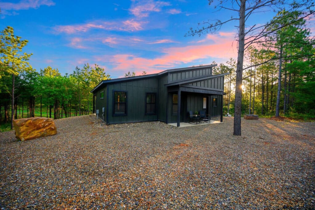 This modern dark cabin nestled in the pines feels like your own private escape, especially as the sun sets and the whole place glows against that perfect blue-pink sky.