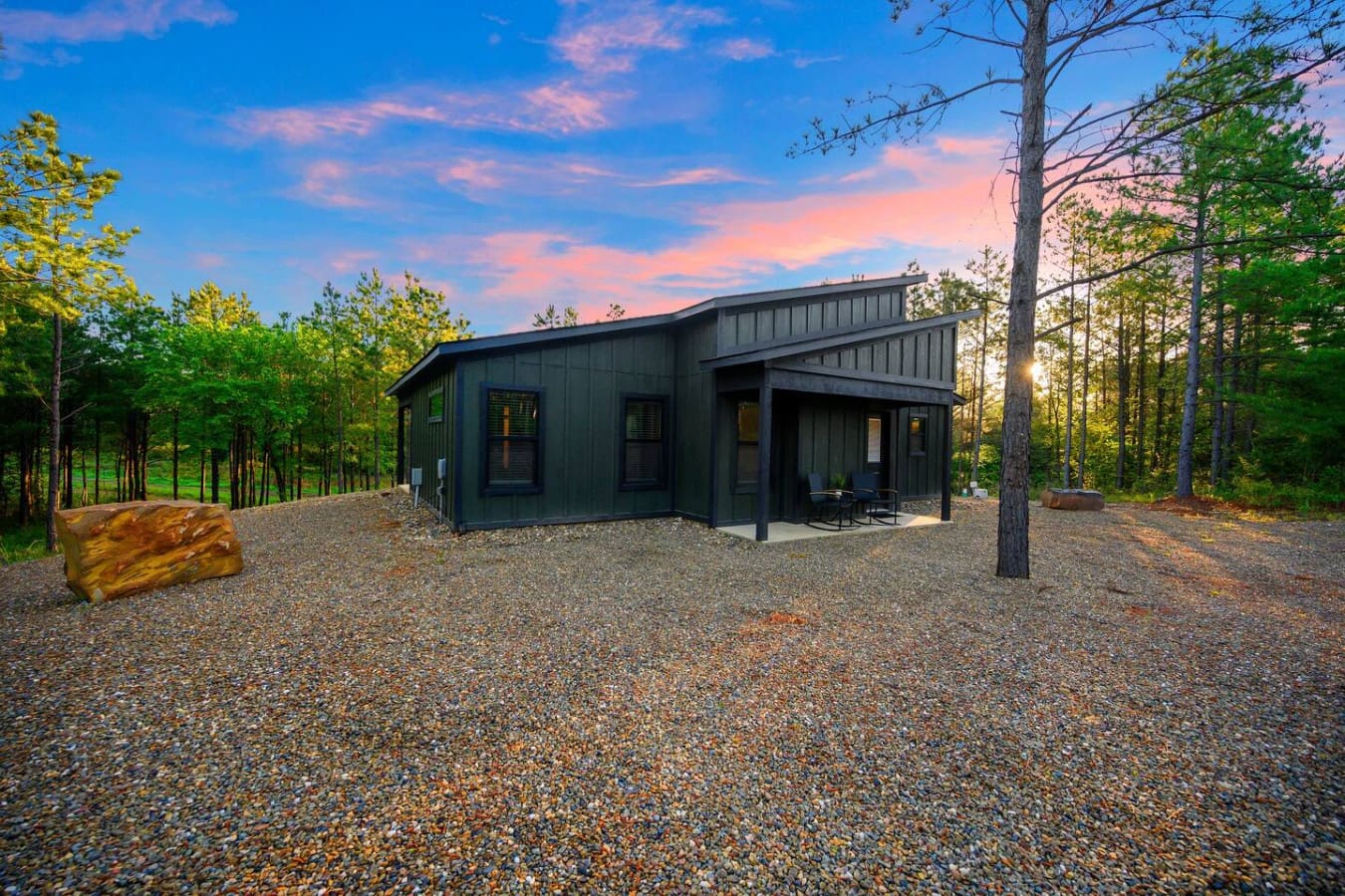 This modern dark cabin nestled in the pines feels like your own private escape, especially as the sun sets and the whole place glows against that perfect blue-pink sky.