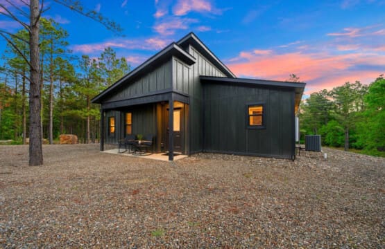 This sleek modern black cabin feels like your own hidden getaway tucked deep in the pines, with those warm interior lights glowing as the sky puts on a show overhead.