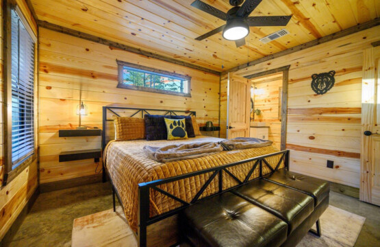 This bedroom is basically the perfect cabin retreat with those gorgeous wood walls, a black metal bed frame loaded with cozy blankets, and paw print pillows that add just the right touch of personality to the space.