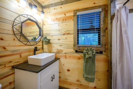 This log cabin bathroom somehow makes you feel like you're getting a spa treatment in the woods, with that sleek white vessel sink sitting pretty against all the warm wood paneling.