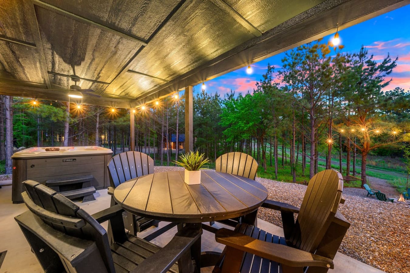 As the sun melts into those perfect pink and blue hues, you've got your hot tub warming up on one side, a fire pit crackling in the middle, and a whole forest of towering pines making you feel like you're the only people on earth.