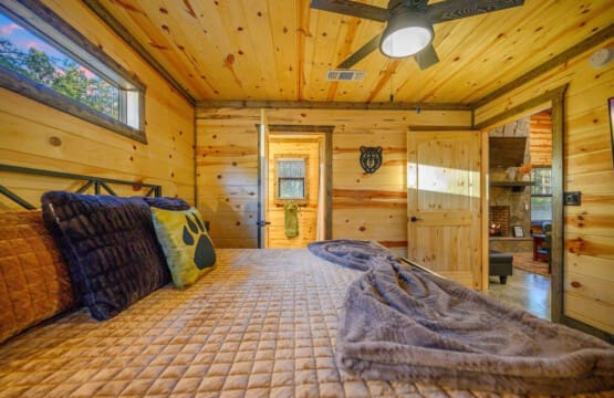 Wake up in this cozy wood-lined bedroom and you'll pretty much never want to leave—knotty pine walls, a comfy bed piled with blankets, that bear head watching over you, and windows showing off the trees right outside.