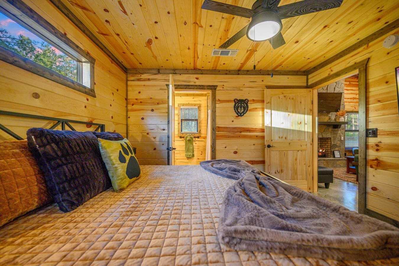 Wake up in this cozy wood-lined bedroom and you'll pretty much never want to leave—knotty pine walls, a comfy bed piled with blankets, that bear head watching over you, and windows showing off the trees right outside.