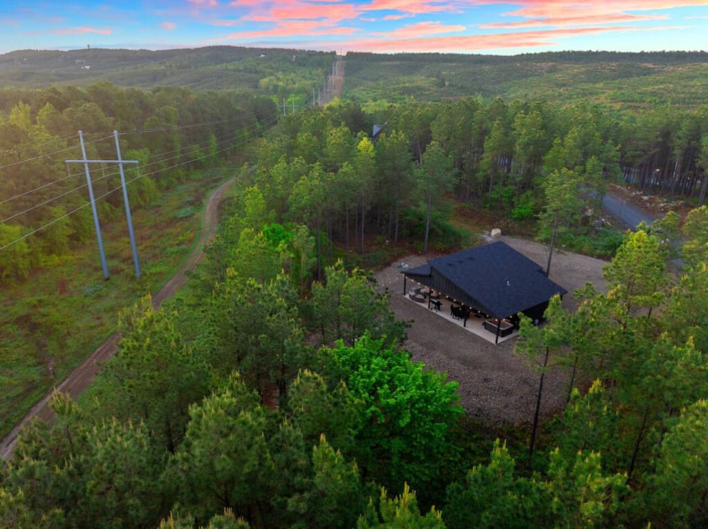Nestled deep in the pines with a river winding through the trees, this modern cabin feels like your own completely private forest escape, especially as the sun paints the sky in those perfect pink and blue hues.