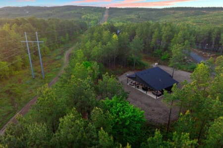 Nestled deep in the pines with a river winding through the trees, this modern cabin feels like your own completely private forest escape, especially as the sun paints the sky in those perfect pink and blue hues.