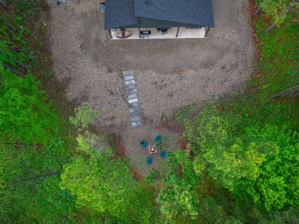 From above, you can see exactly why this place is so special—a cozy modern cabin nestled in the pines with a fire pit, stepping stones, and plenty of gravel space to just breathe and take it all in.
