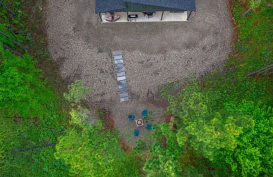 From above, you can see exactly why this place is so special—a cozy modern cabin nestled in the pines with a fire pit, stepping stones, and plenty of gravel space to just breathe and take it all in.