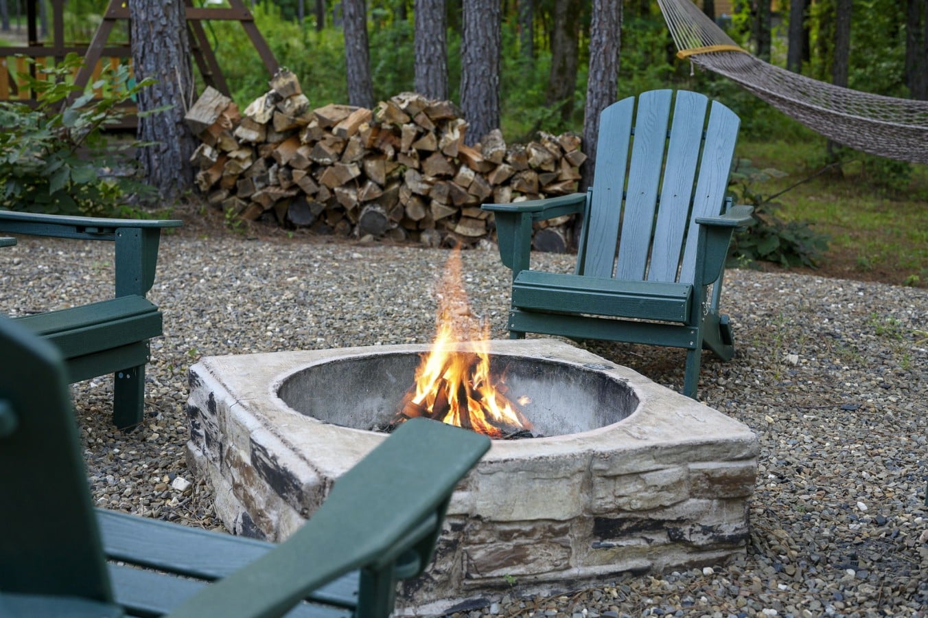 Circular fire pit with Adirondack seating for evenings under the trees.