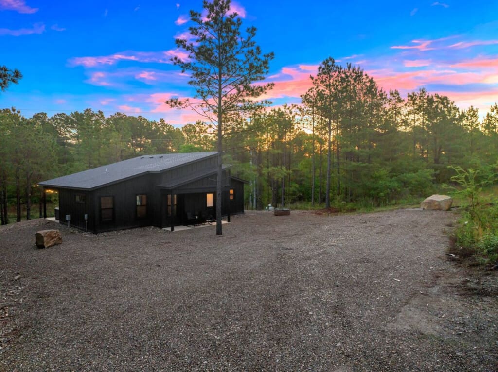 This sleek modern black cabin tucked into the forest feels like stepping into your own private retreat, especially with that stunning twilight sky lighting everything up just right.