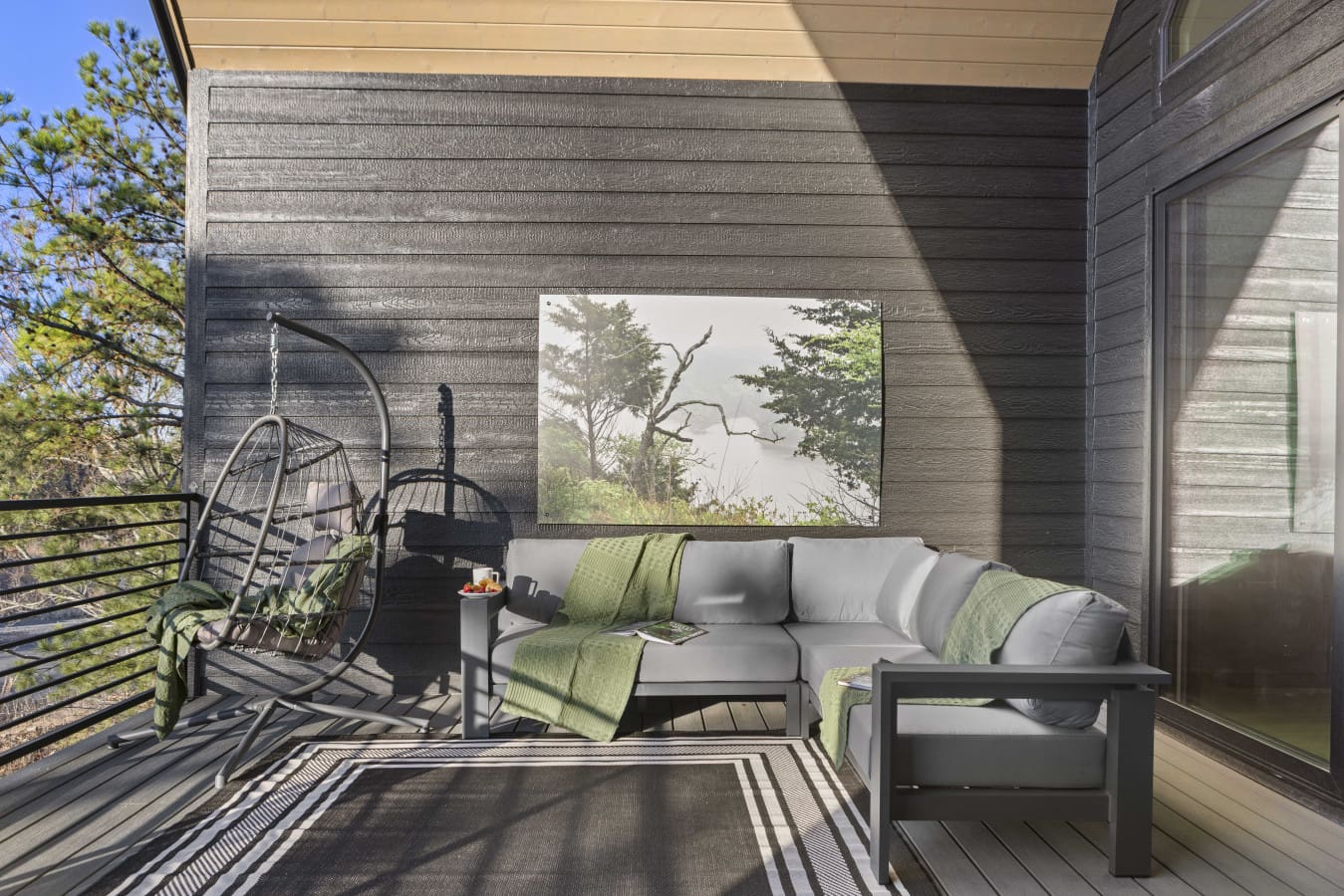Unwind on this serene covered deck with hanging chairs, modern seating, and panoramic forest views.