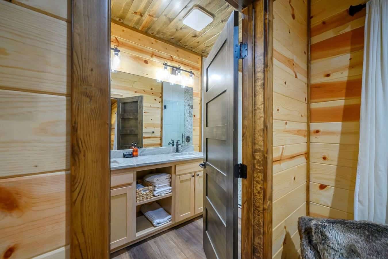 This beautiful log cabin bathroom features custom wood finishes, a spacious vanity with ample storage, and plenty of natural light.