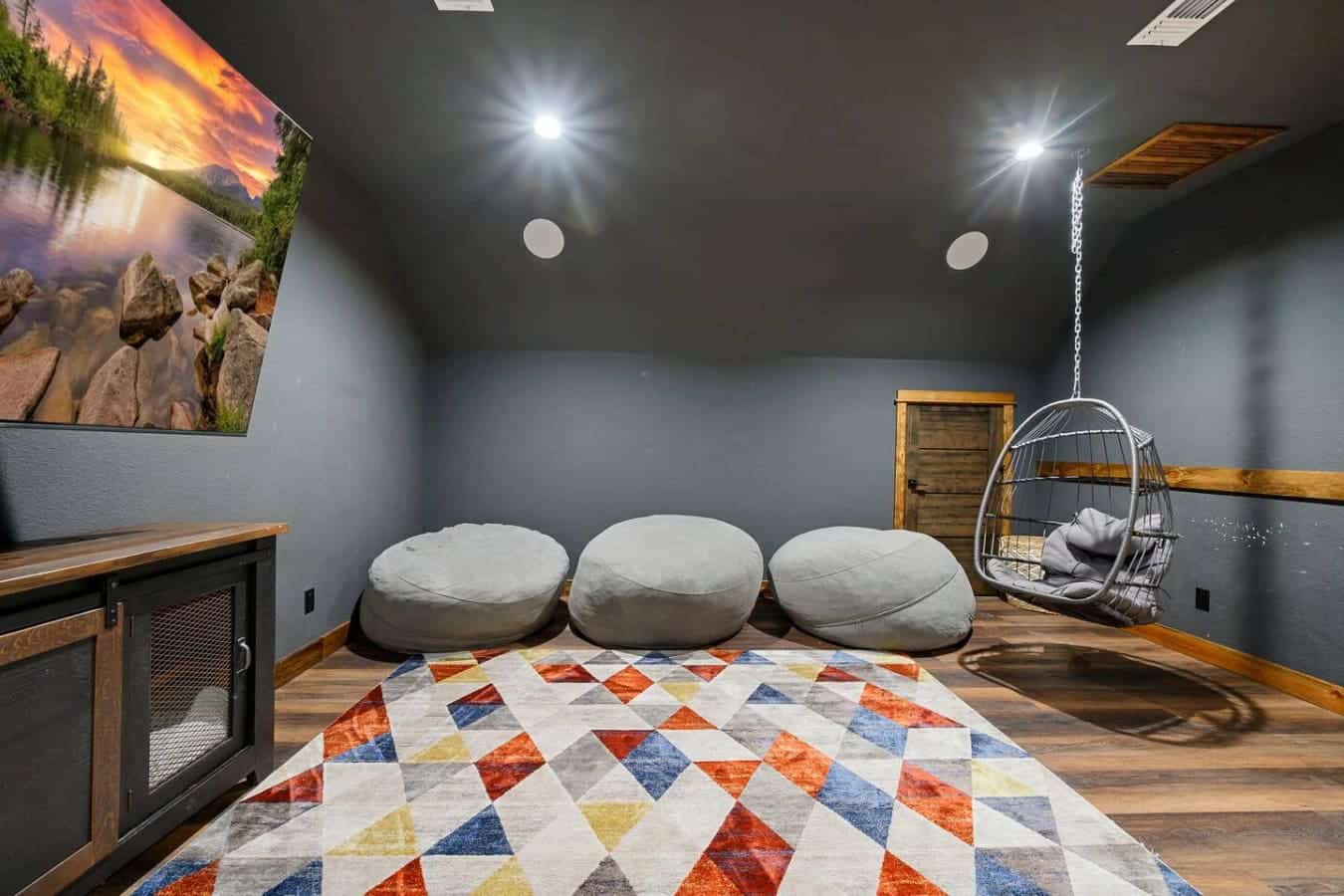 This cozy media room is perfect for entertaining with plush seating, a hanging chair, and ambient lighting throughout.