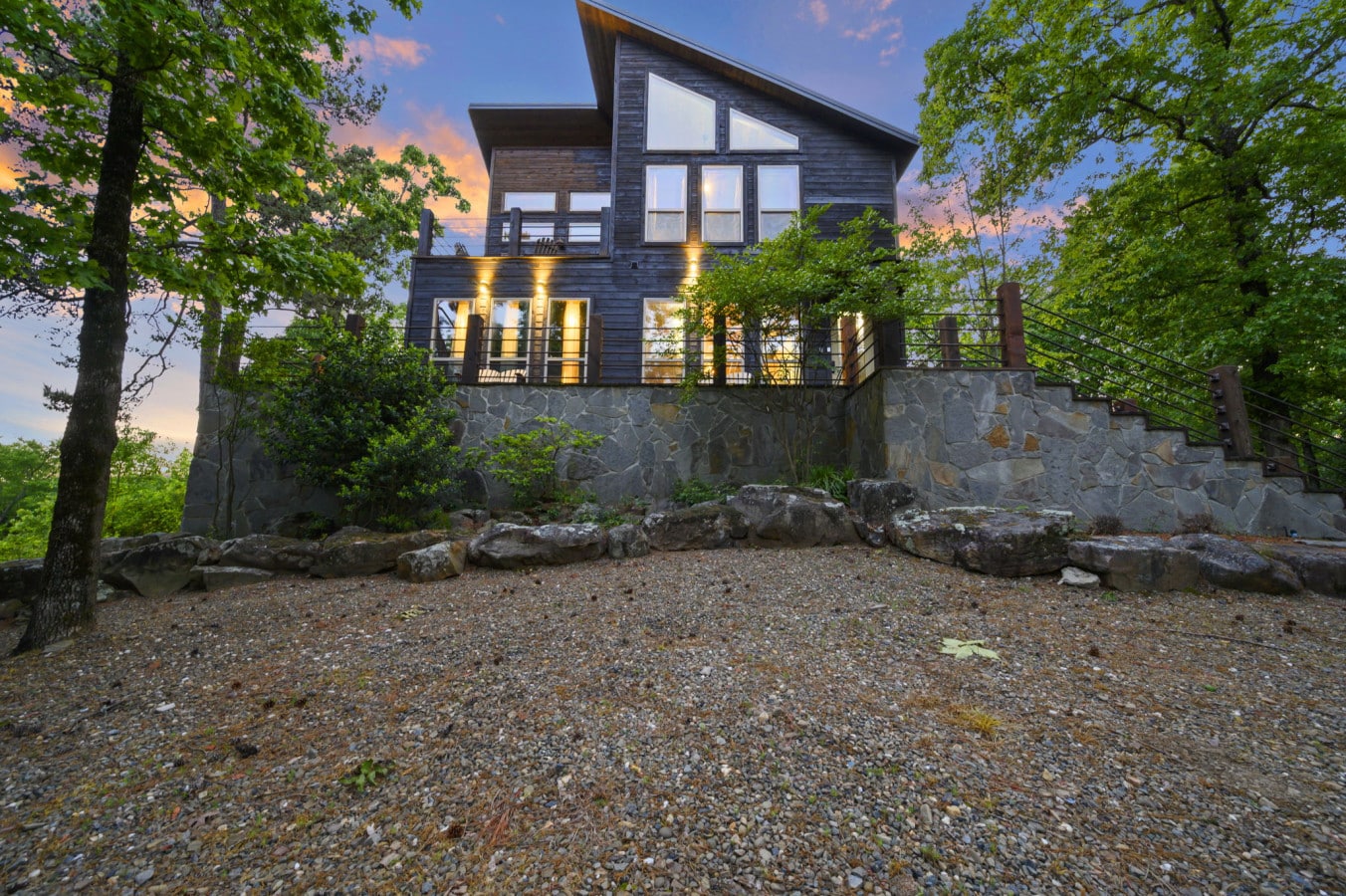 The cabin is beautifully lit at dusk, showcasing its modern wood-sided architecture.