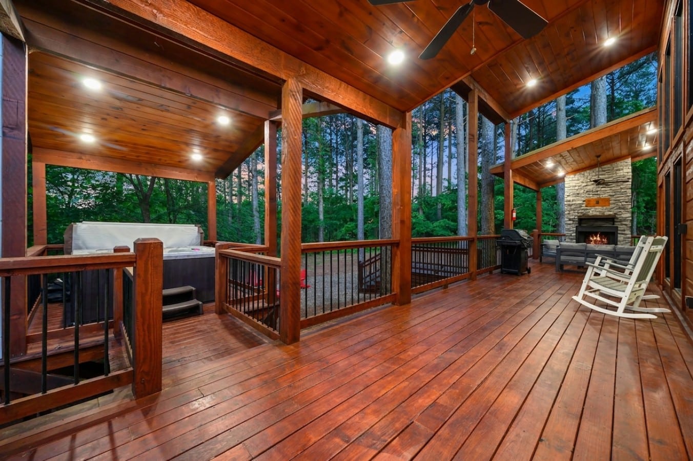 Hot tub, fireplace, and rocking chairs share one spectacular covered deck under the pines.