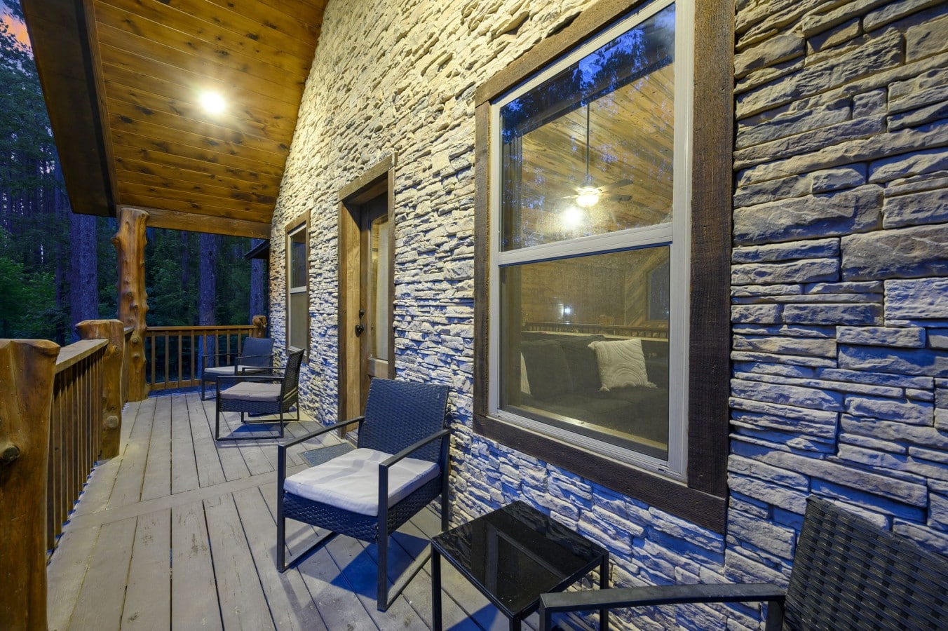 The full stone facade and cushioned wicker seating make this deck feel like a luxury resort.