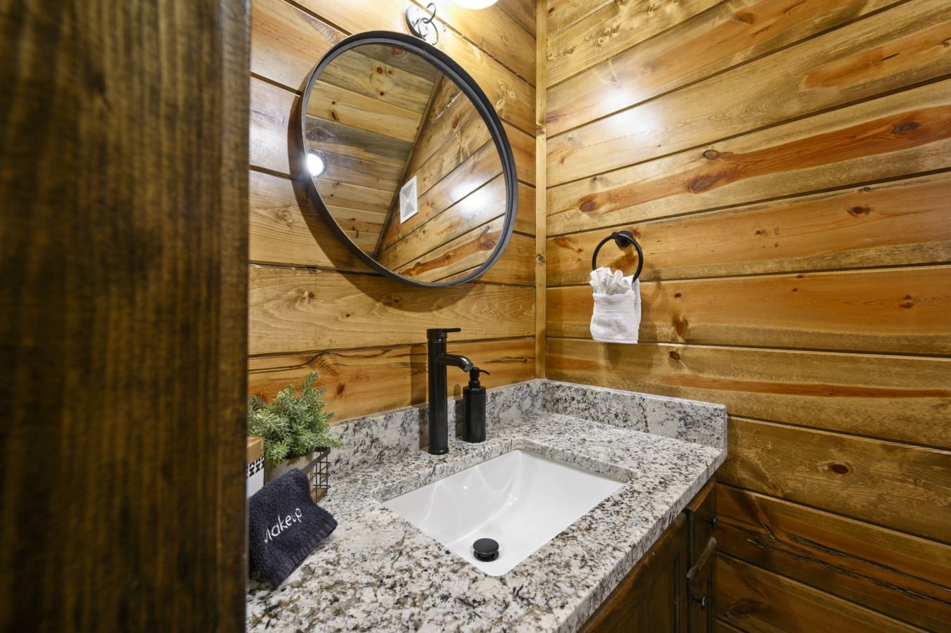 Sleek black fixtures against warm wood walls bring rustic charm and modern style together.