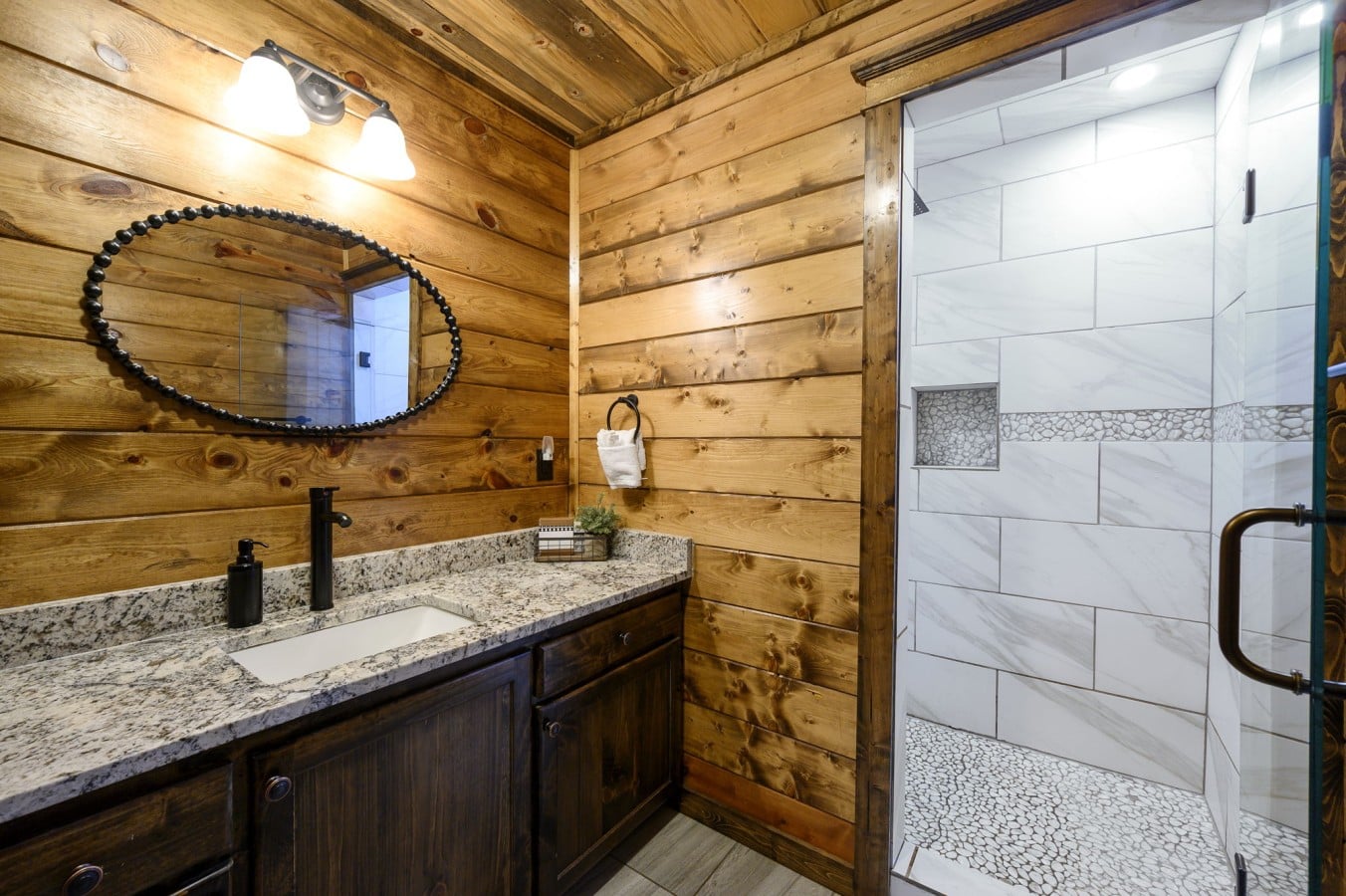 Even the guest bath impresses with a glass-enclosed tiled shower and pebble-floor details.