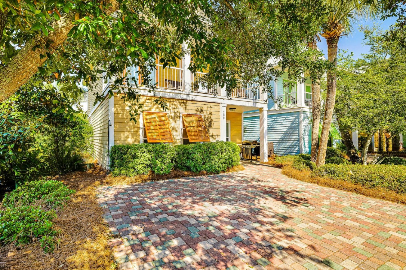 Step beneath a canopy of trees and into a colorful multi-balcony beach cottage escape.