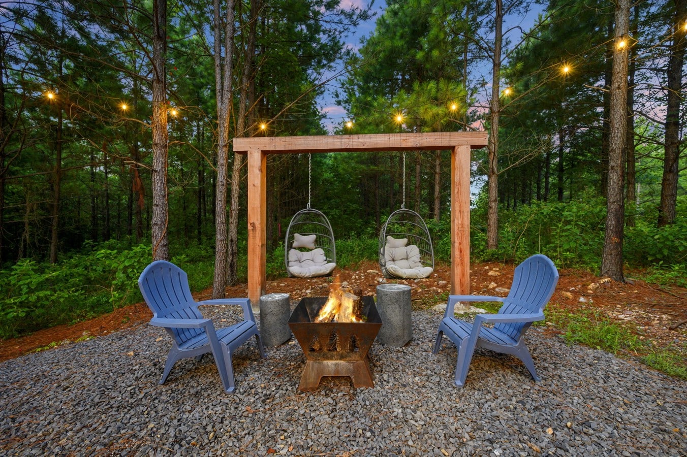 Fire pit seating under string lights for quiet evenings in the trees.