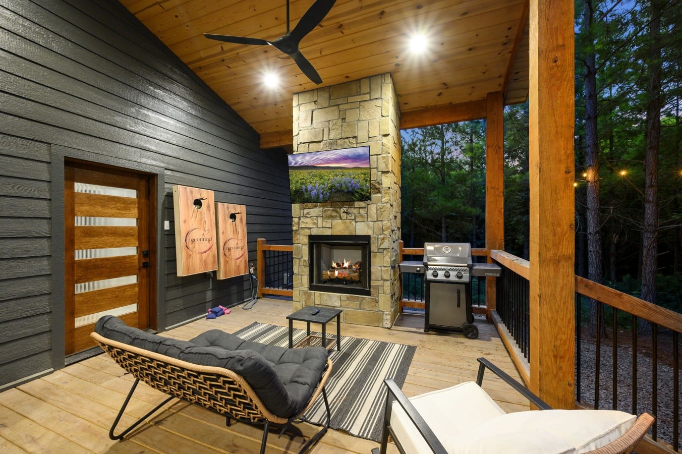 Covered deck with outdoor fireplace, TV, grill, and lounge seating.