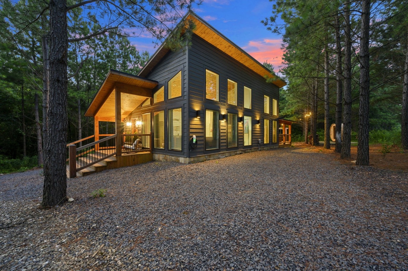 Wide twilight exterior showing the modern cabin tucked among the pines.