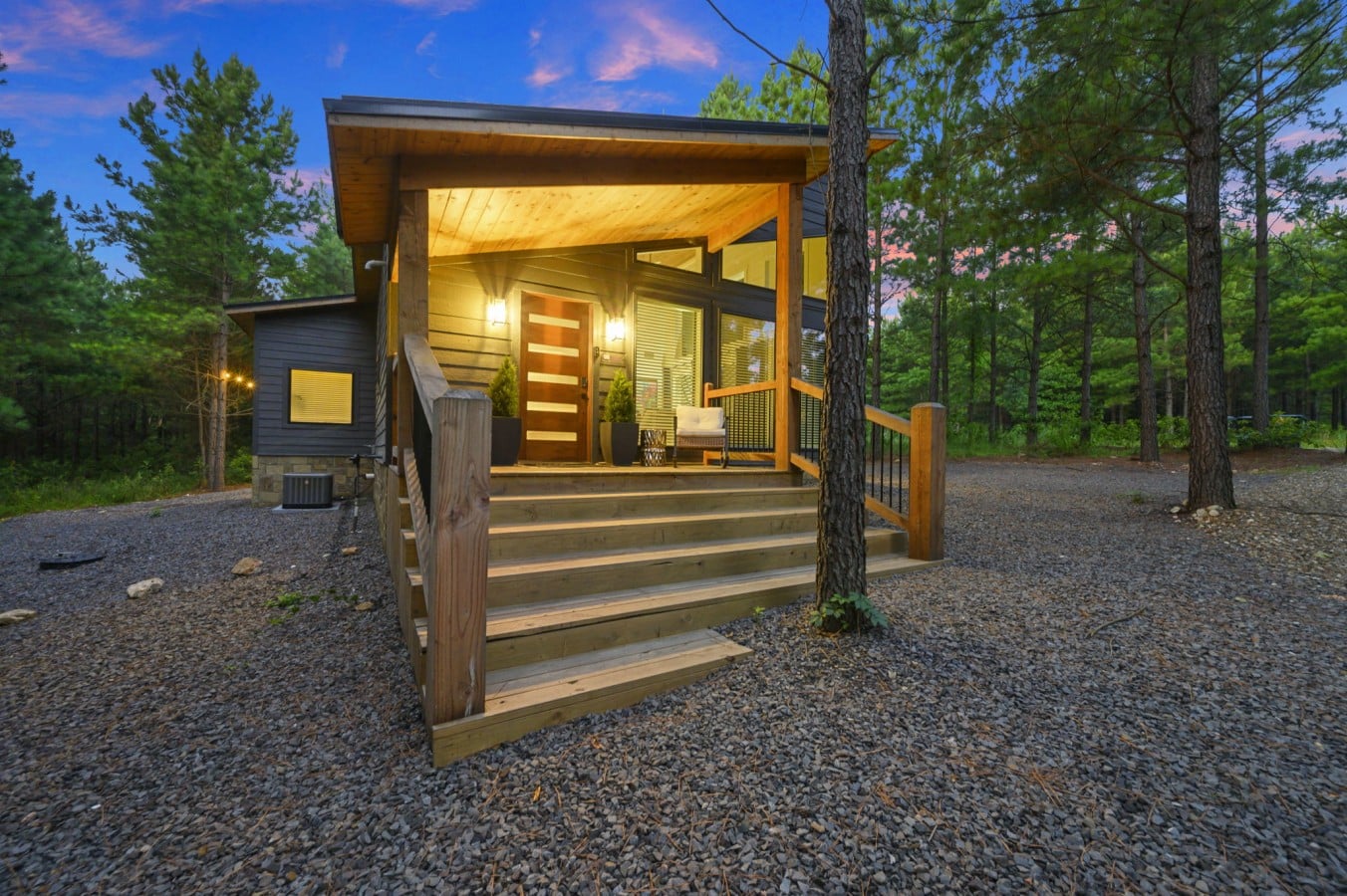 Covered front porch with modern entry, rocking chair, and welcome mat.