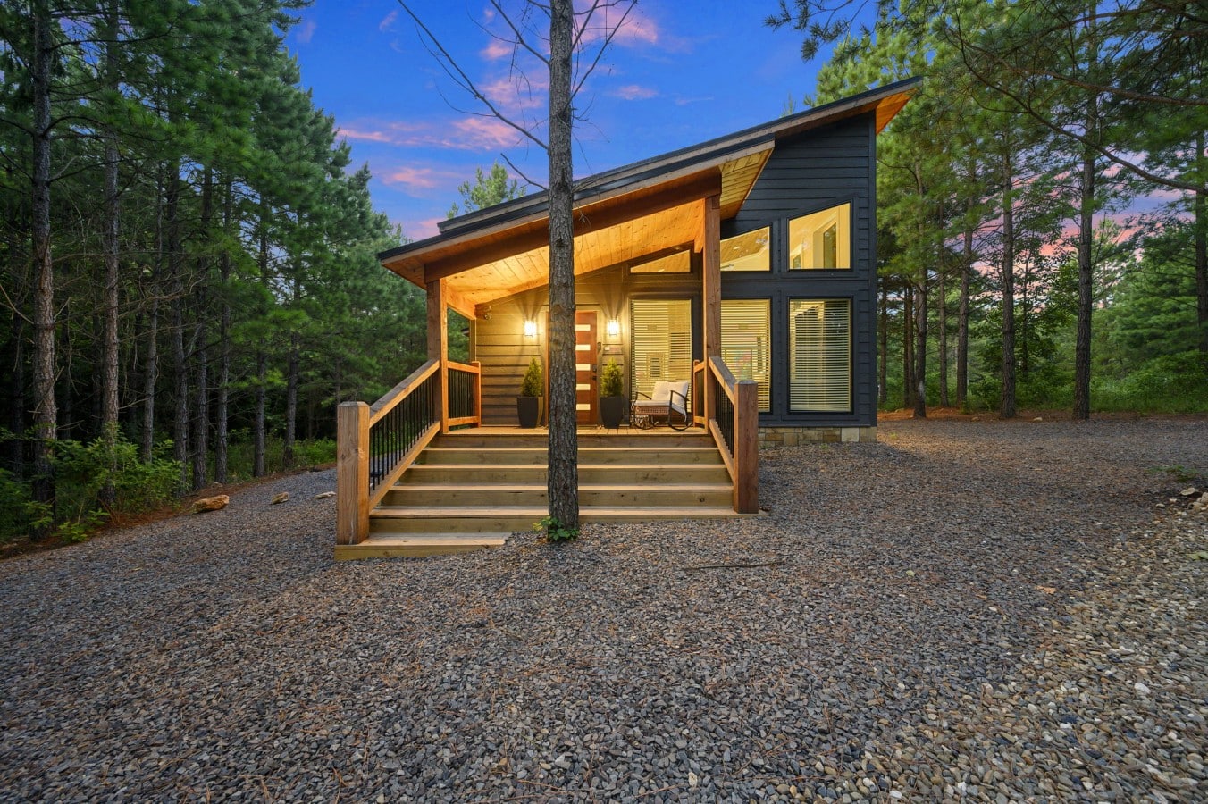 Front exterior view with warm cabin lights and a sunset sky.
